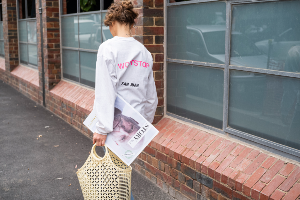 Woman walking away and there is a STORYmag magazine underneath her arm